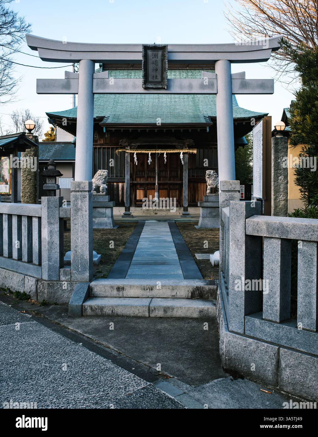 Una vista tranquilla di un piccolo santuario shintoista urbano a Kanazawa, Yokohama, Giappone. Un cancello torii in pietra, guardiani di cani leoni e corda shimenawa sono i benvenuti sul sito Foto Stock