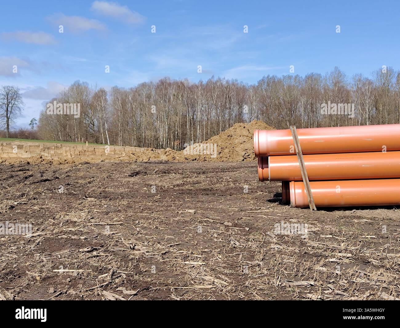 Cantiere con tubi in pvc e un mucchio di terra nel paesaggio rurale. Foto Stock