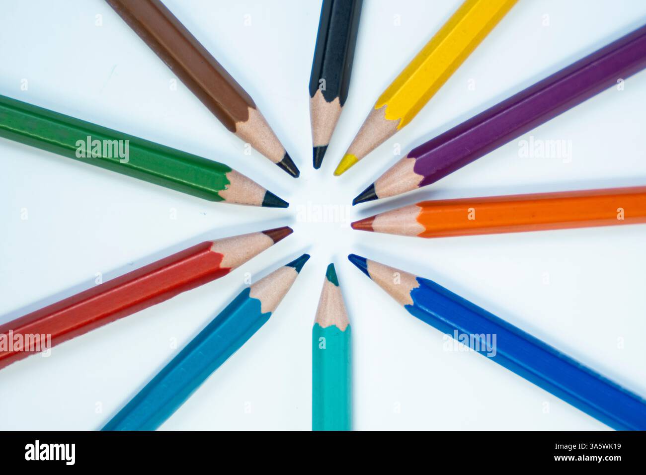 Una foto creativa di colori a matita disposti in un motivo circolare su uno sfondo bianco. Ideale per campagne artistiche ed educative. Foto Stock