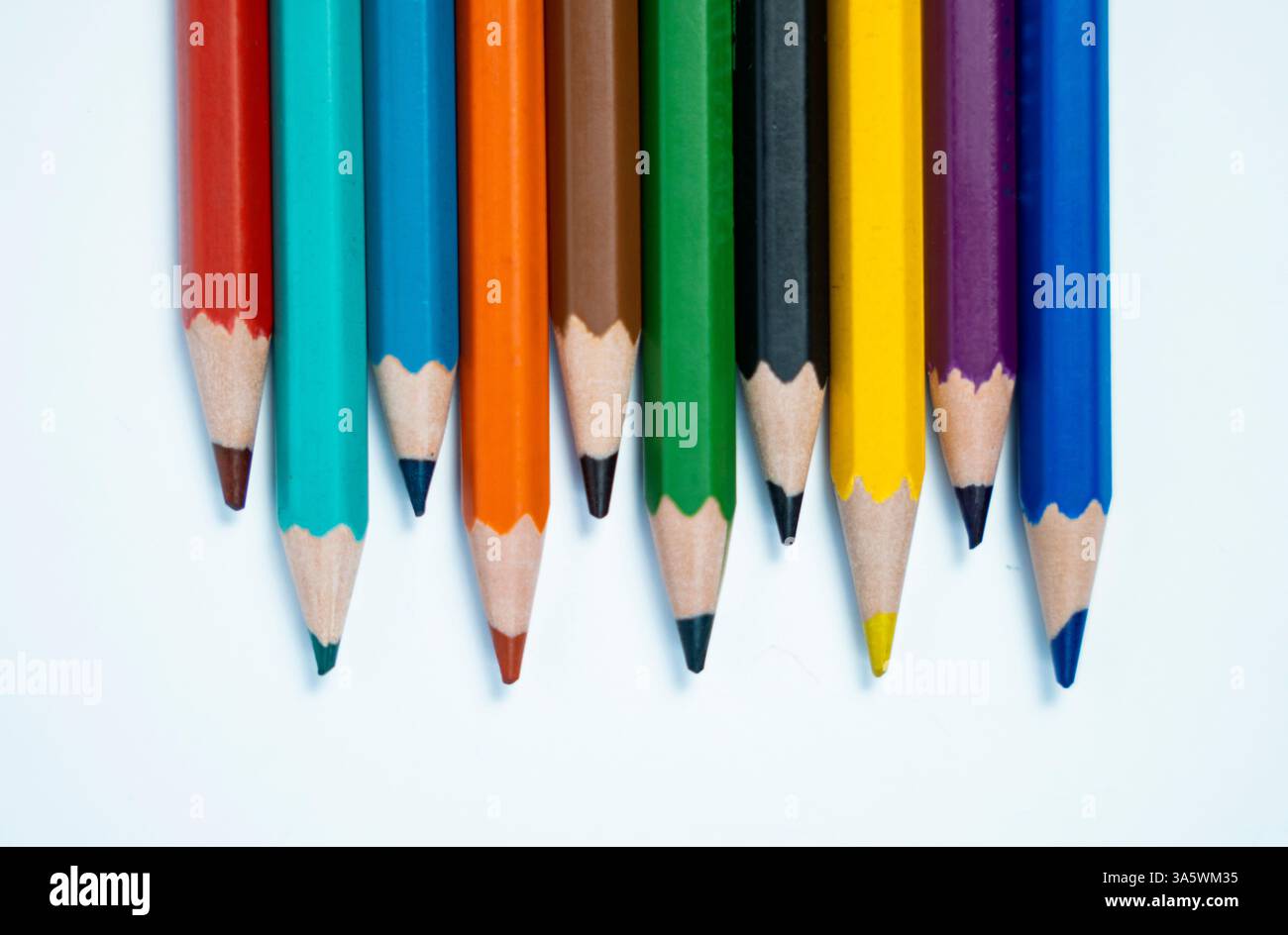 Una foto creativa di colori a matita disposti in un motivo artistico casuale su uno sfondo bianco. Ottimo per contenuti artistici ed educativi. Foto Stock