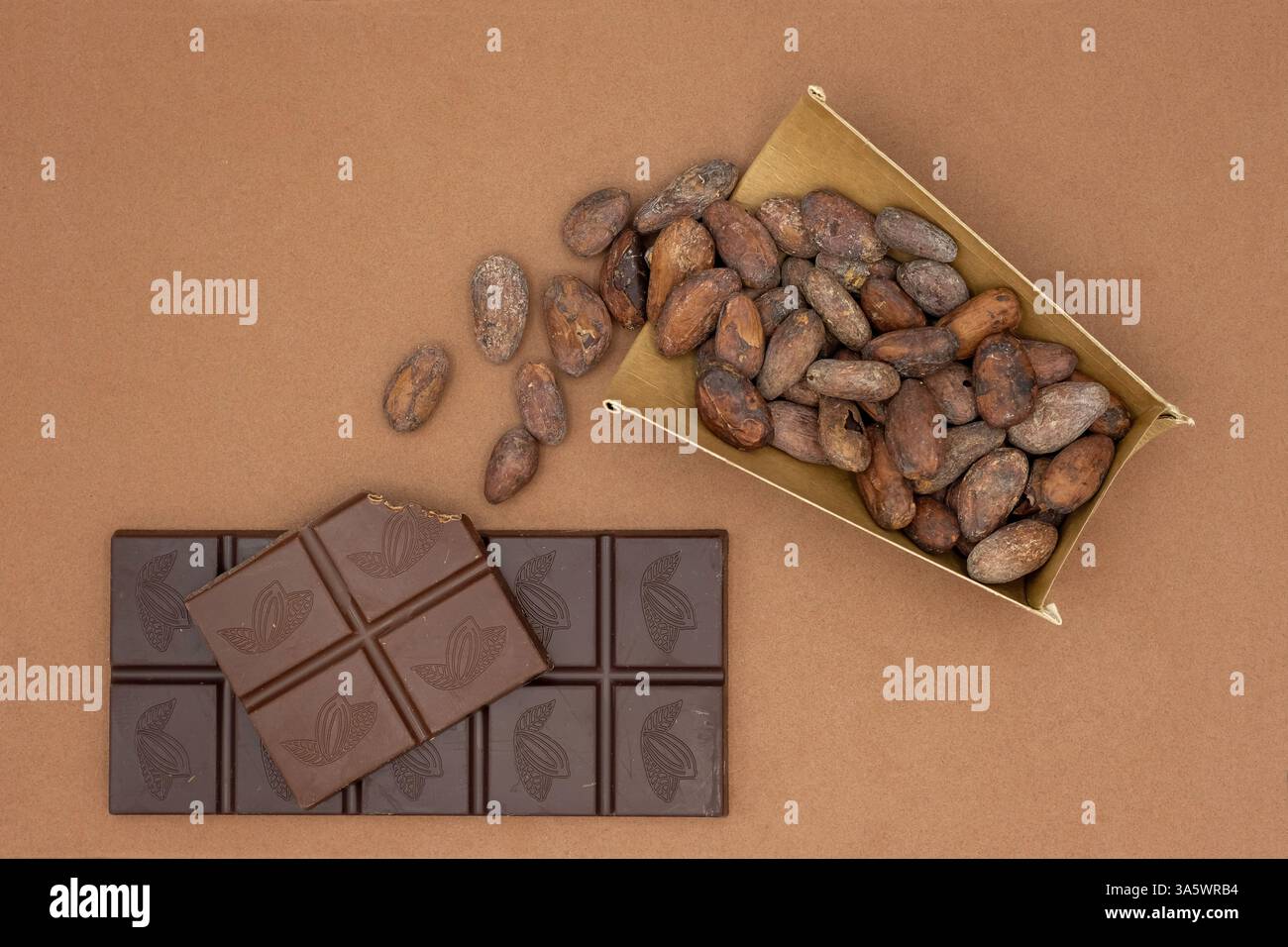 I chicchi di cacao dal bicchiere di carta usa e getta fuoriescono sulle barrette di cioccolato. Dal cacao crudo al cioccolato di lusso. Foto Stock