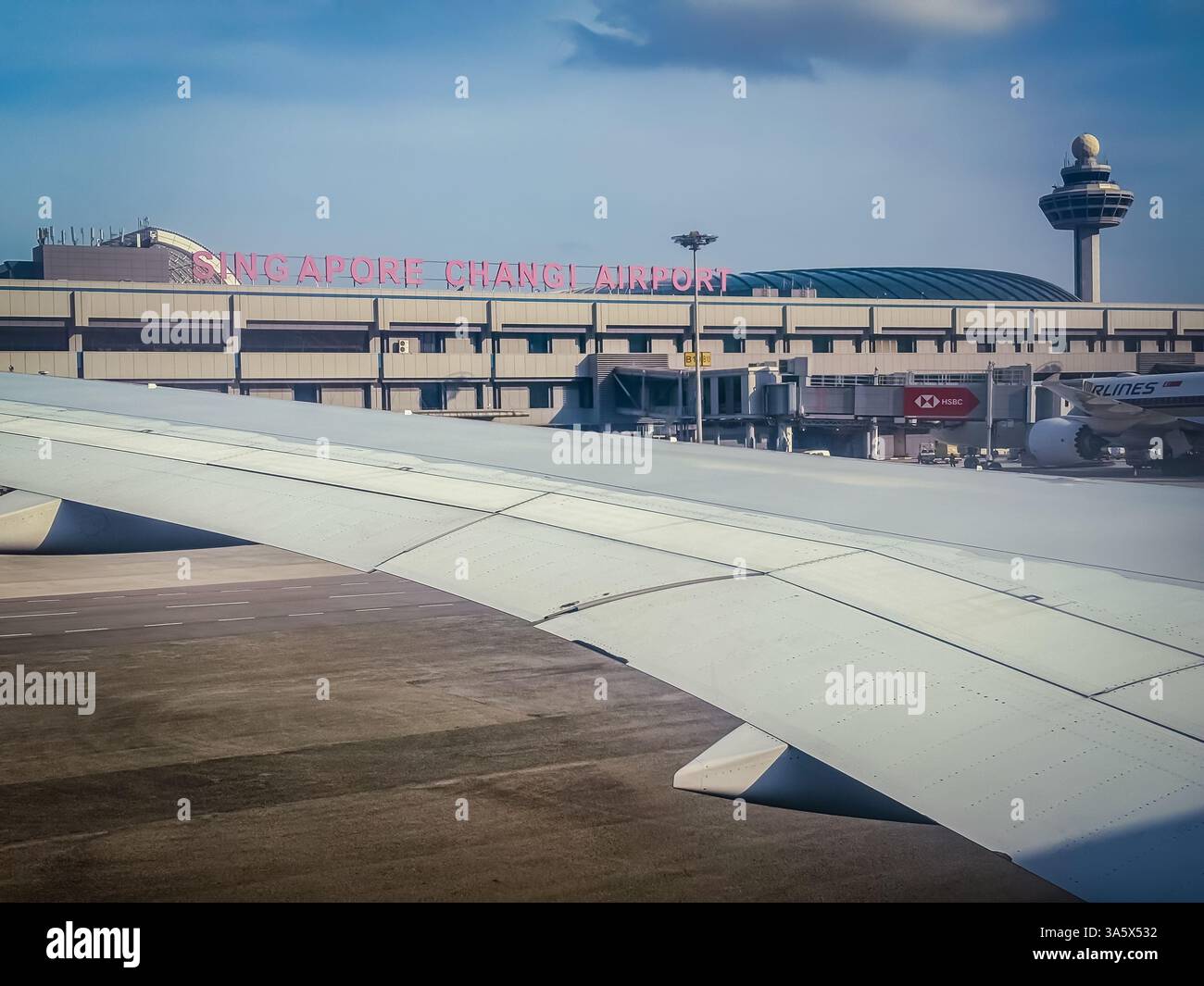 Aeroporto Changi di Singapore visto dall'aereo. Il terminal dell'aeroporto, la torre di controllo e l'ala degli aerei sono visibili. Foto Stock