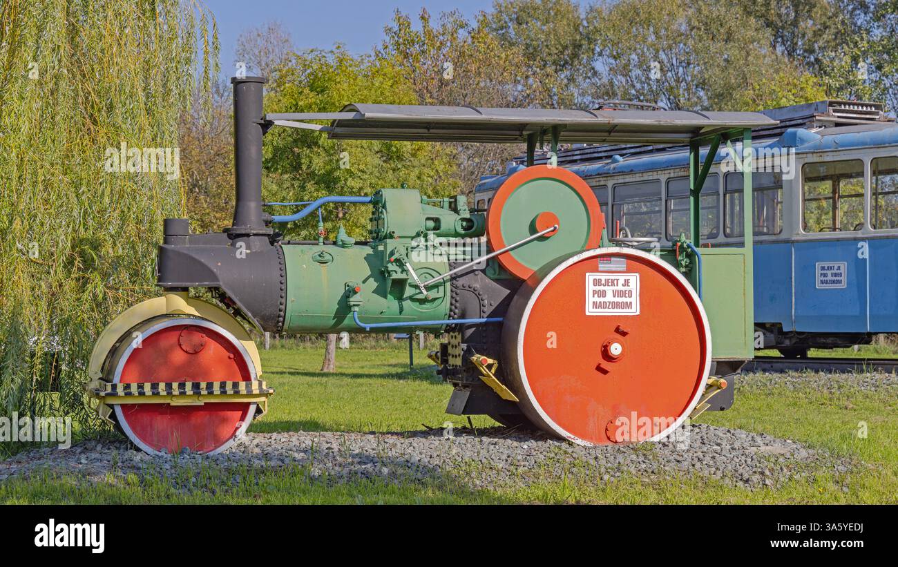 Slavonski Brod, Croazia - 22 ottobre 2024: Macchina a rulli a vapore e vecchio tram elettrico presso il Parco industriale Turistico Djuro Djakovic Museo all'aperto gratuito. Foto Stock