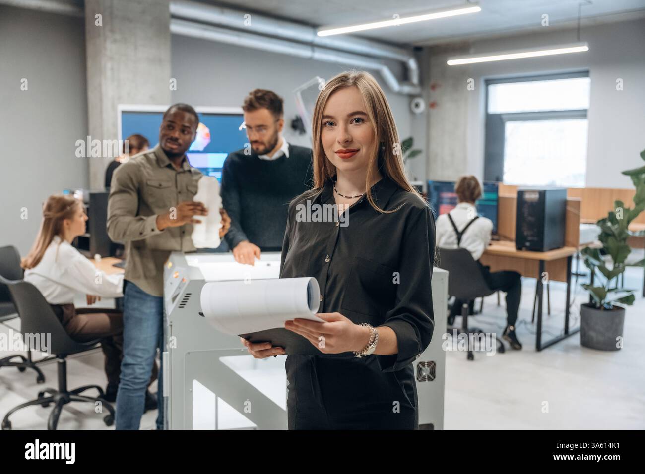 La donna è davanti ai colleghi. Le persone sono in ufficio vicino alla stampante 3D. Foto Stock