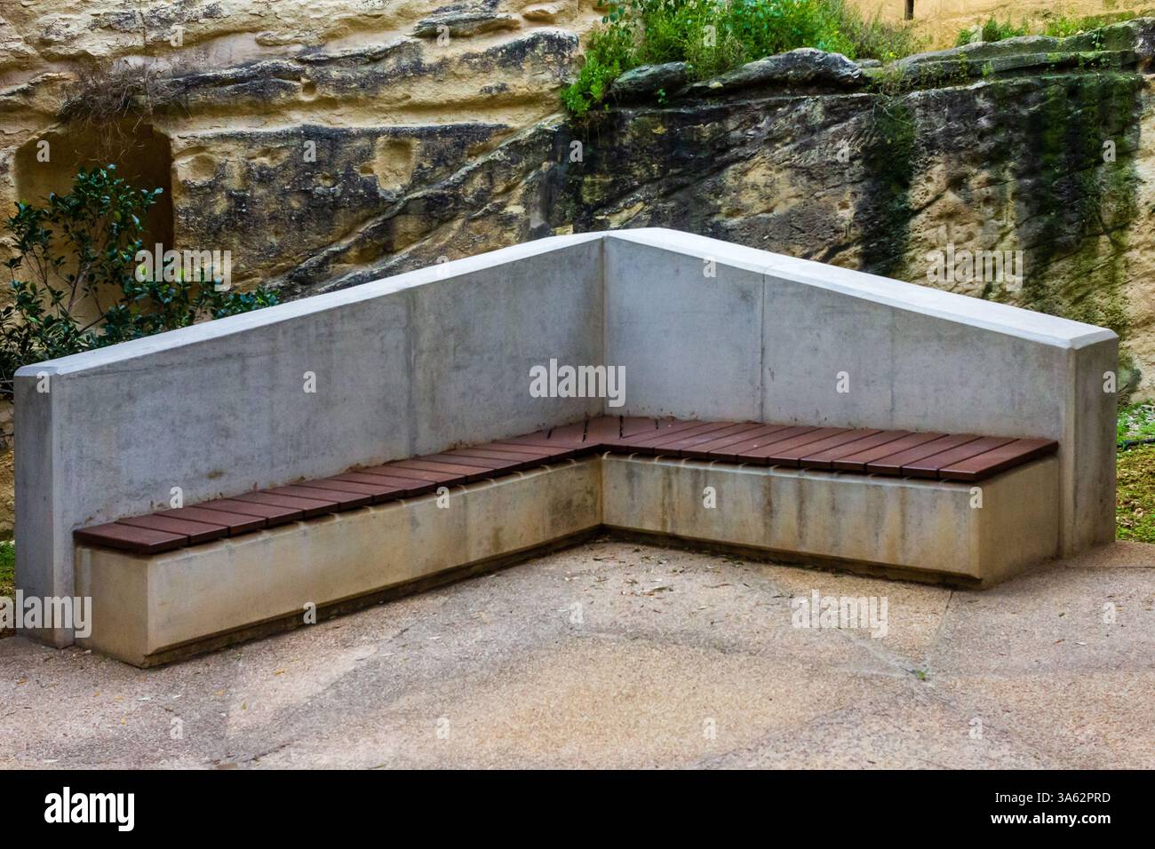 Panca moderna e minimalista in cemento e legno in un ambiente naturale all'aperto Foto Stock