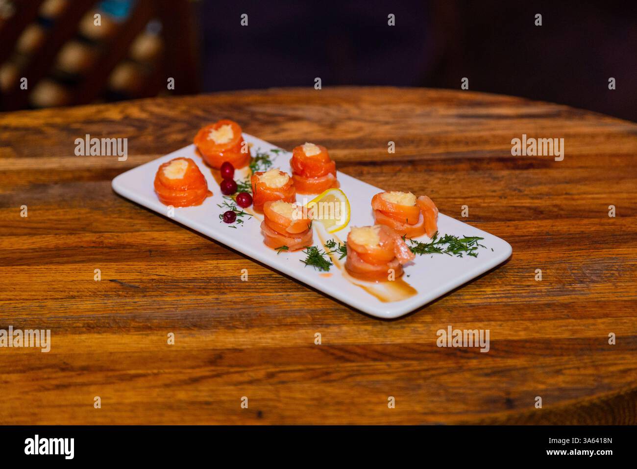 Appetitosi involtini di pesce rosso con ripieno all'interno su un piatto bianco e un tavolo di legno in un ristorante. vista dall'alto Foto Stock