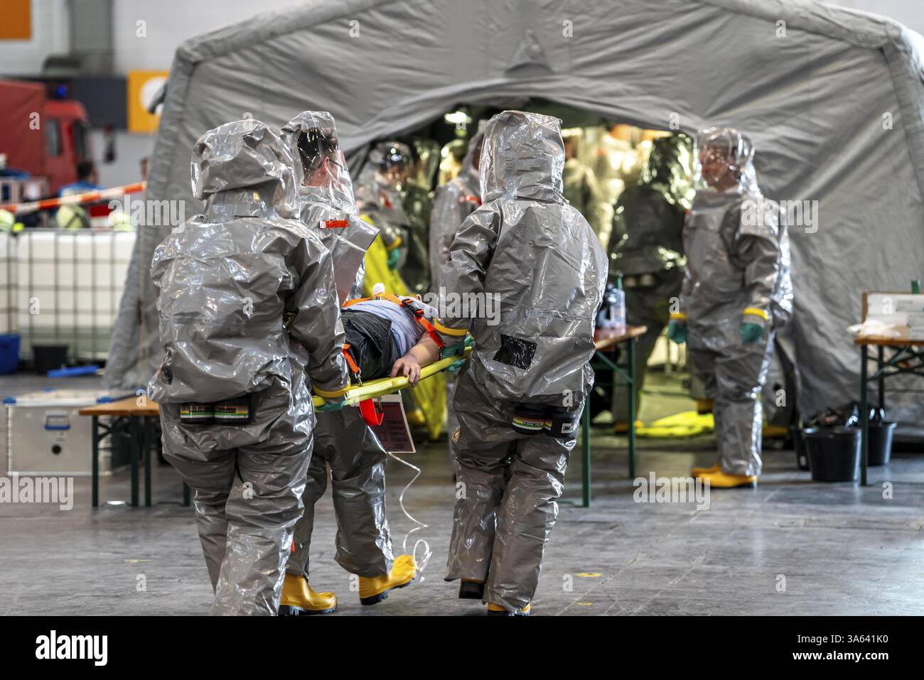 La decontaminazione delle persone ferite dopo un presunto incidente che coinvolge sostanze pericolose, i vigili del fuoco e le organizzazioni umanitarie esercitano la creazione di un Foto Stock