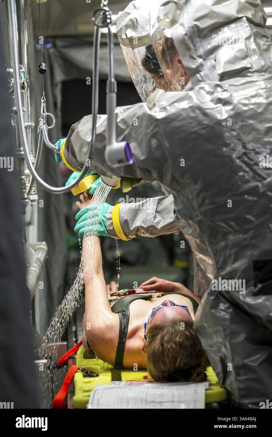 La decontaminazione delle persone ferite dopo un presunto incidente che coinvolge sostanze pericolose, i vigili del fuoco e le organizzazioni umanitarie esercitano la creazione di un Foto Stock