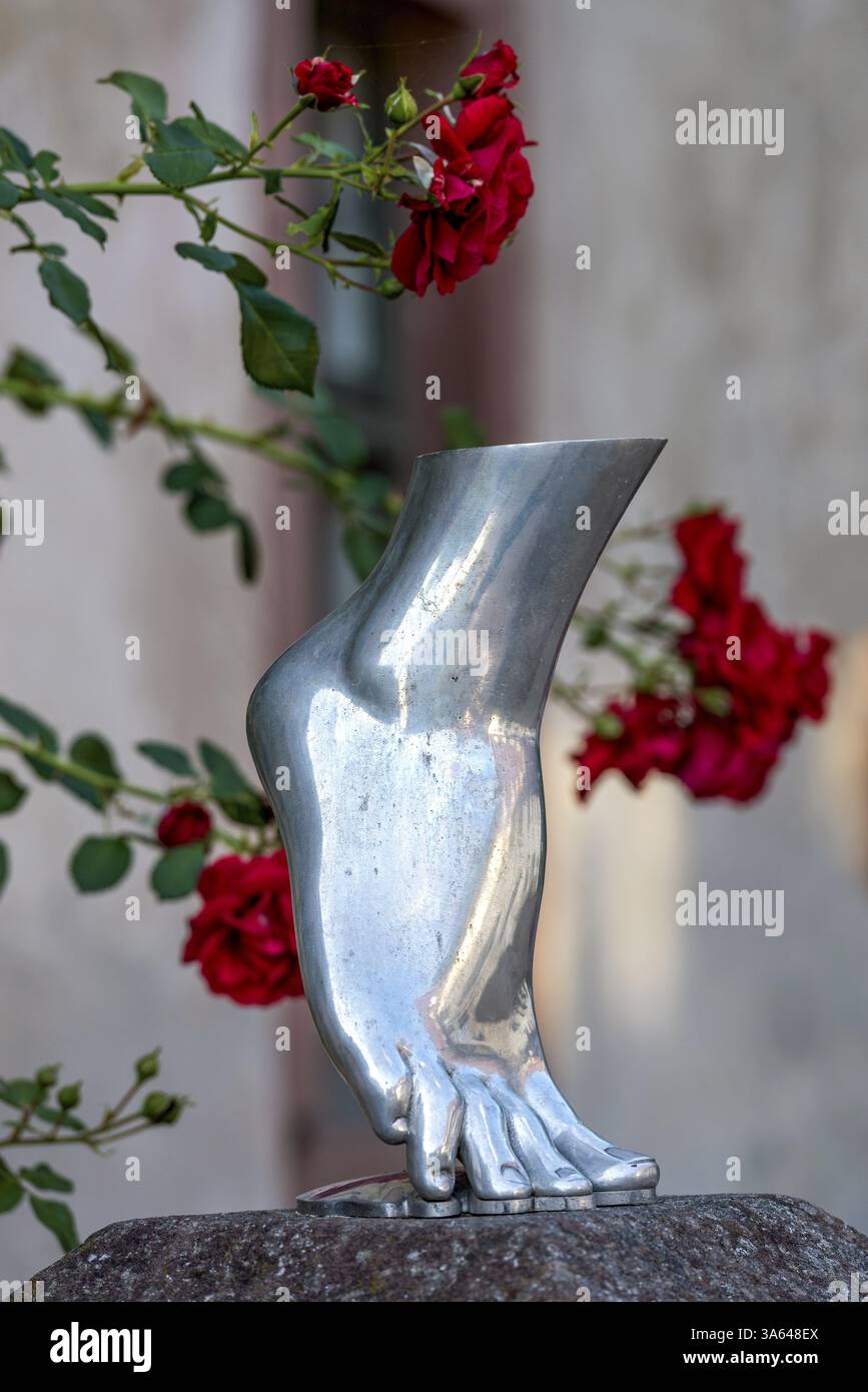 Piede di una donna in punta di piedi, scultura color argento, metallo lucido, rose rosse sullo sfondo, Steinbach, Michelstadt, Odenwald, Assia, Germania, E. Foto Stock