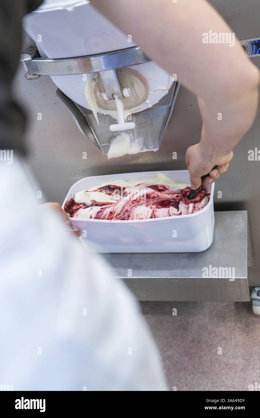 Una persona che confeziona gelato alla frutta in un contenitore bianco, gelato artigianale, Haselstaller Hof, Wildberg, Foresta Nera, Germania, Europa Foto Stock
