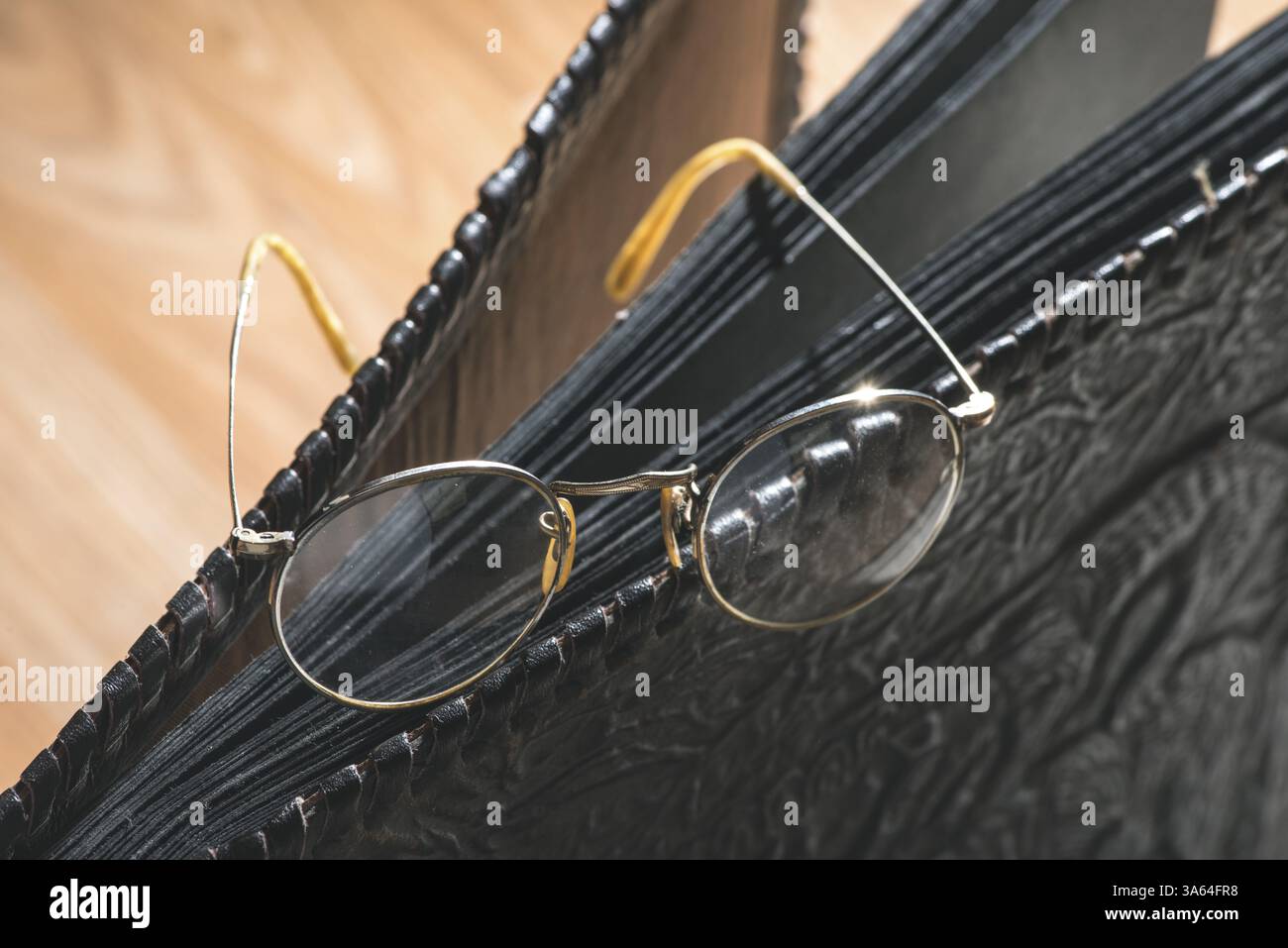 Vecchi occhiali rotondi vintage e album fotografico in pelle Foto Stock