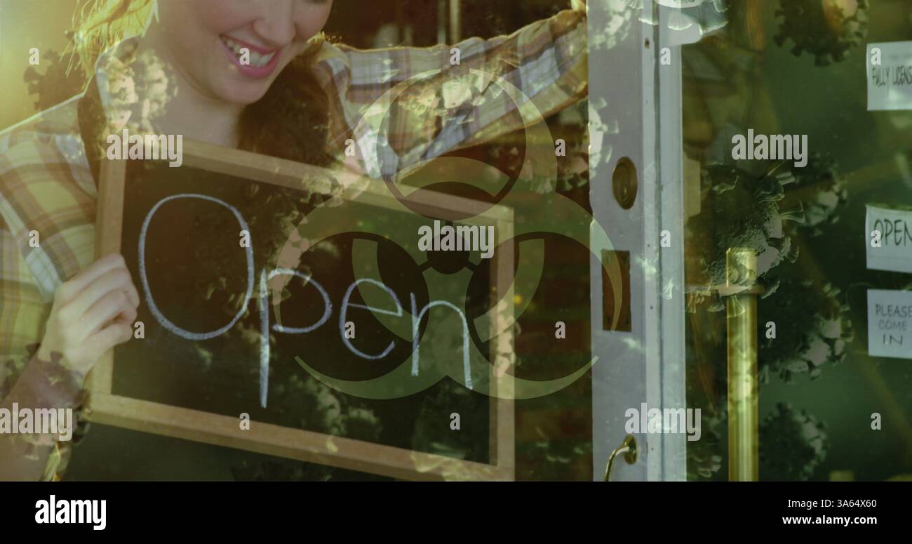 Donna sorridente che tiene in mano un cartello aperto all'ingresso del negozio, accogliendo i clienti Foto Stock