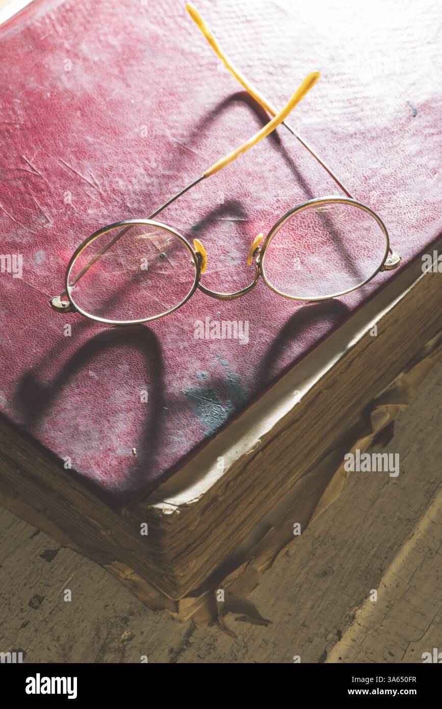Vecchio vintage occhiali rotondi e vecchio libro. Luce bassa Foto Stock