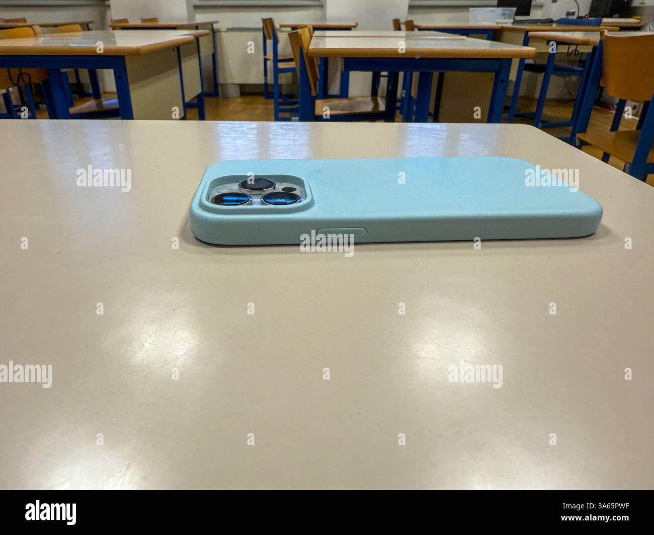 Smartphone con custodia blu sulla scrivania in aula vuota - concetto di politica di assenza di telefono Foto Stock
