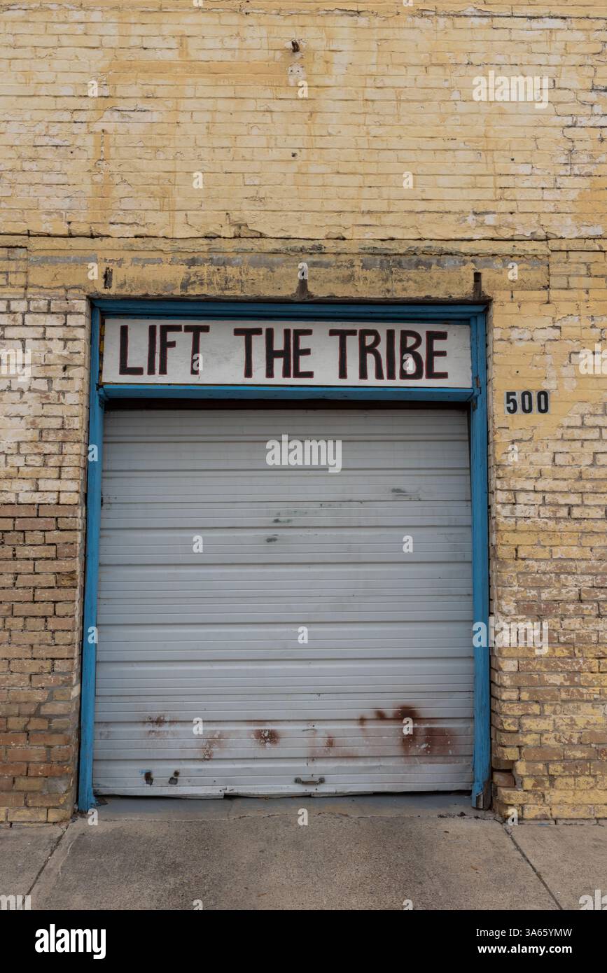Una porta a serranda con le parole Life the Tribe all'esterno di un edificio abbandonato, McAllen, Hidalgo County, Texas, USA. Foto Stock