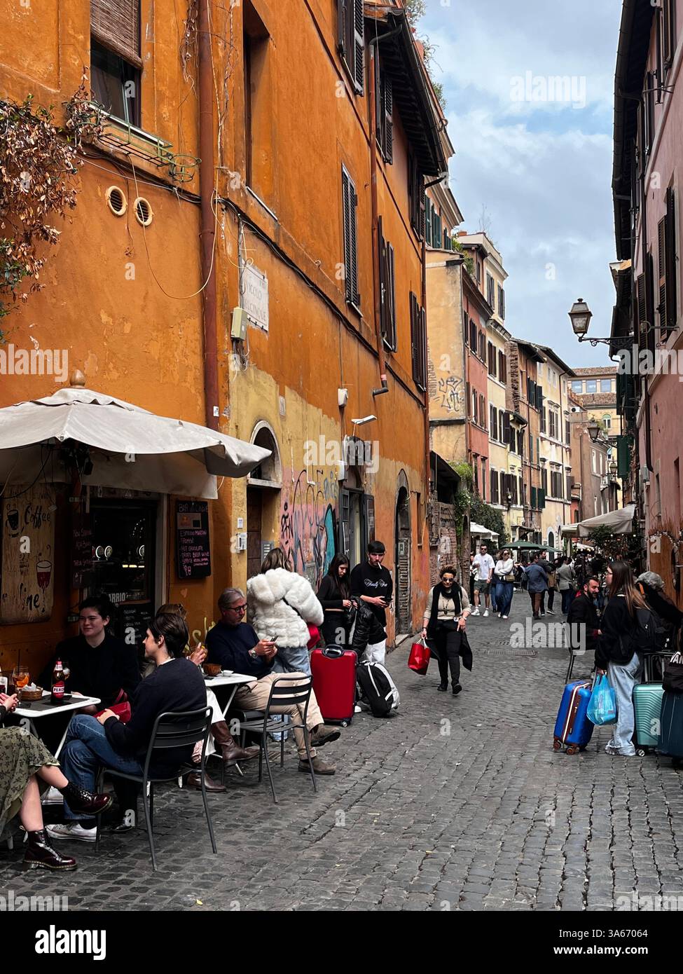 Roma, Italia - marzo 2025 - quartiere Trastevere, stradine acciottolate fiancheggiate da antiche case. Di notte, sia i nativi che i turisti affollano il suo uomo Foto Stock