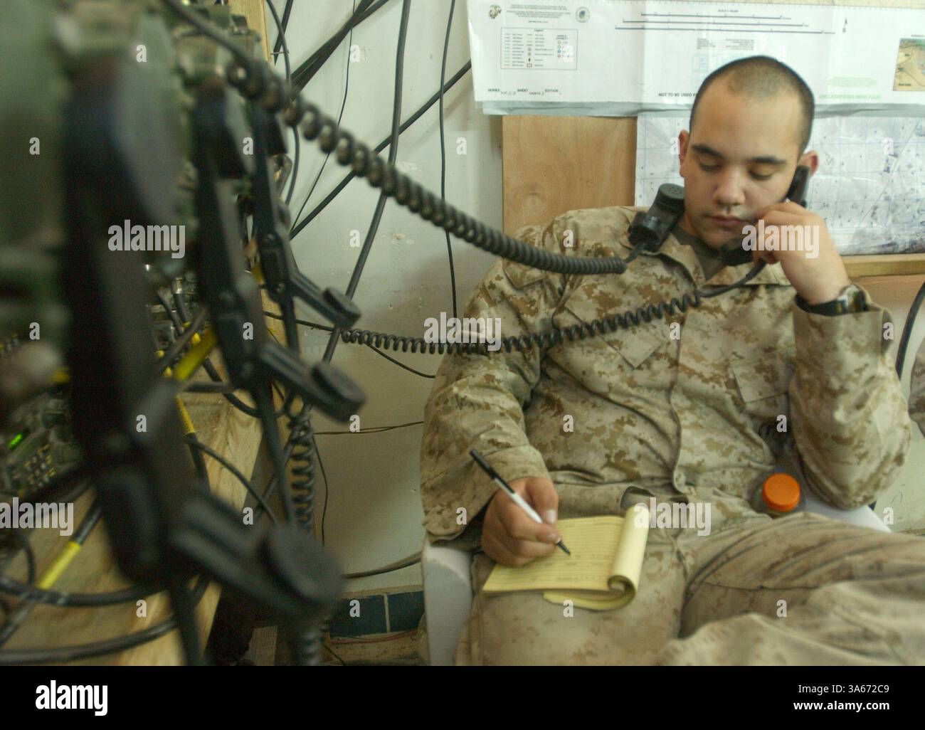 31 agosto 2004; Camp Mahmudiyah, Iraq; aggrovigliato nelle linee telefoniche è l'operatore radio Lance Cpl. MICHAEL A. MARTINEZ, che lavora nel 2nd Battalion, centro operativo del 2nd Marine Regiment. E' compito di Martinez trasmettere informazioni per tenere traccia delle loro unita' sul campo. Foto Stock