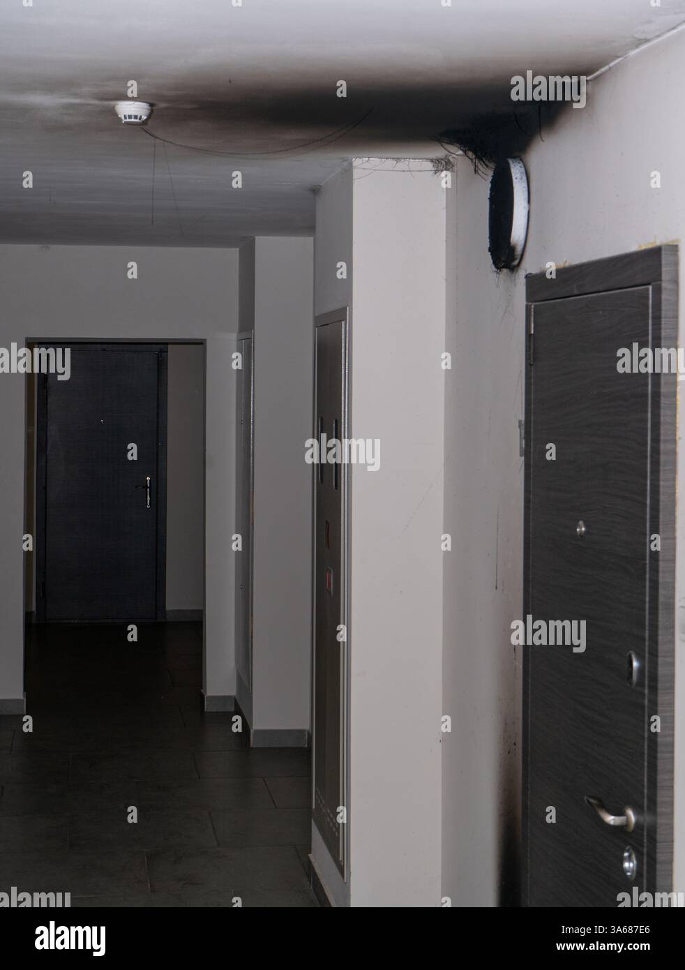 Lampada LED bruciata. Una lampada a paralume sulla parete dopo un incendio. Combustione spontanea e incendio in un edificio residenziale. Sensore di allarme antincendio interno. Porta nel corridoio Foto Stock