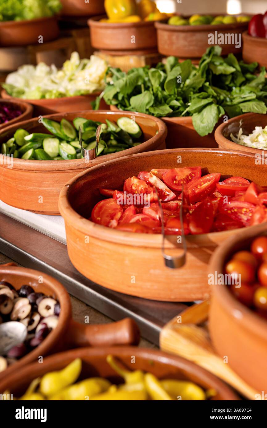 Delizioso tavolo a buffet con verdure biologiche fresche e vivaci in argilla rustica e verdure, con una varietà di piante sane e colorate Foto Stock