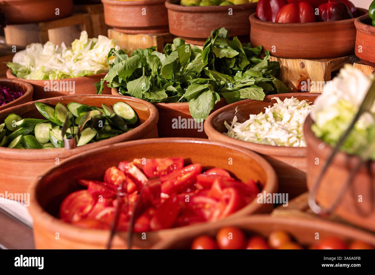 Delizioso tavolo a buffet con verdure biologiche fresche e vivaci in argilla rustica e verdure, con una varietà di piante sane e colorate Foto Stock