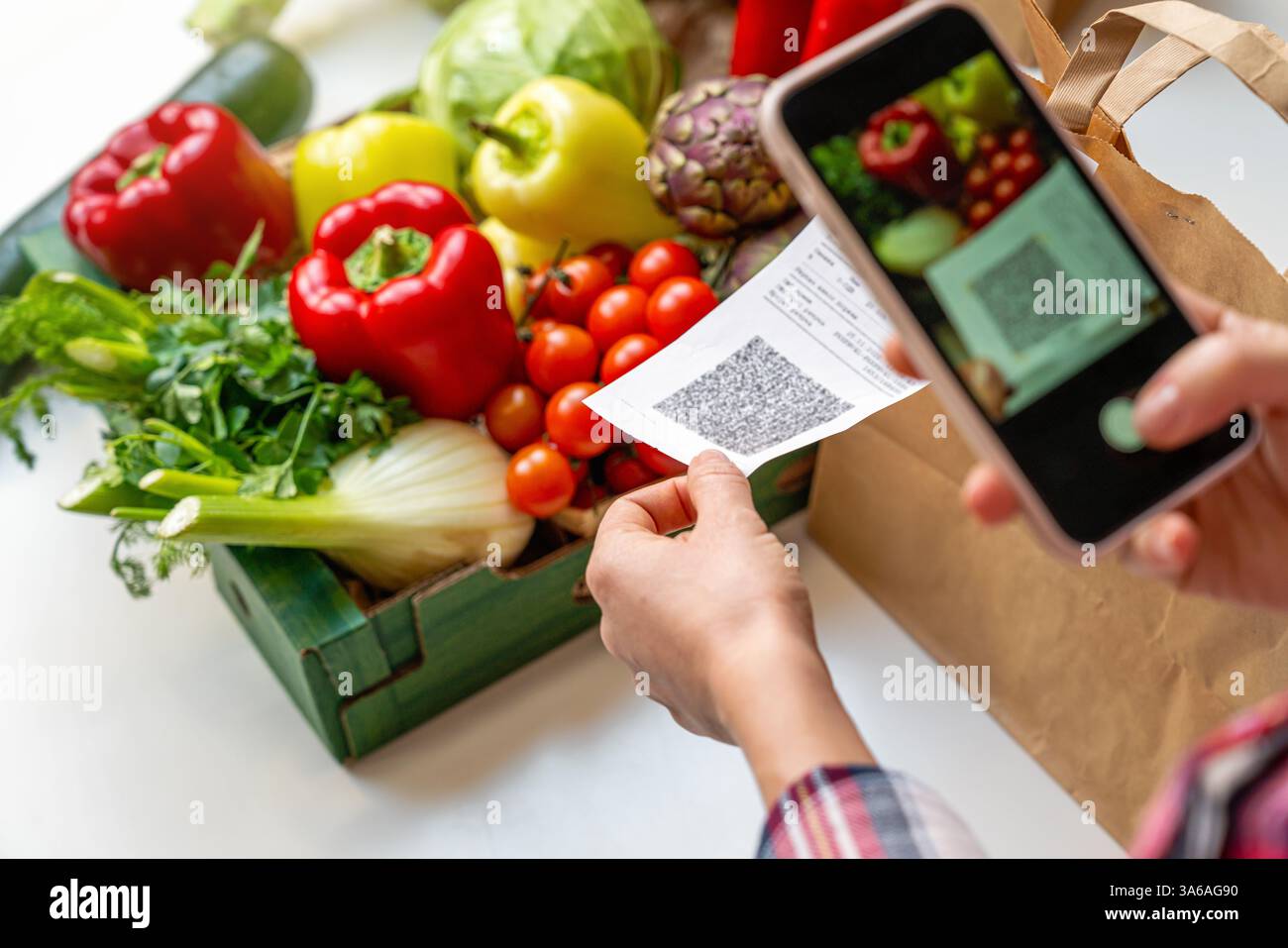 Donna che scansiona il codice qr di ricevimento utilizzando uno smartphone sullo sfondo della scatola con verdure Foto Stock