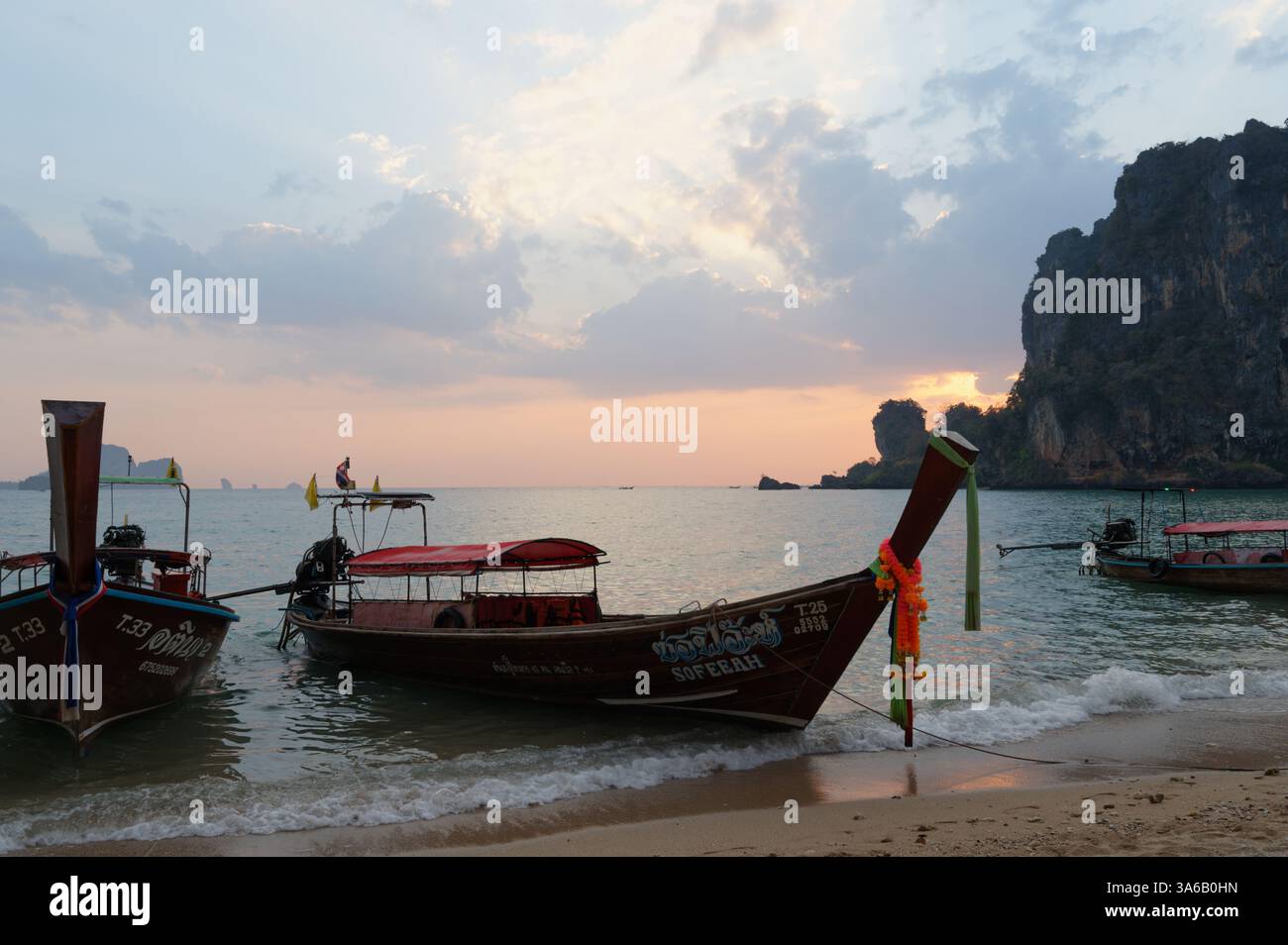 Le tradizionali barche a coda lunga riposano sulla spiaggia sabbiosa, mentre il cielo inizia a oscurarsi sulla spiaggia di Tonsai Foto Stock