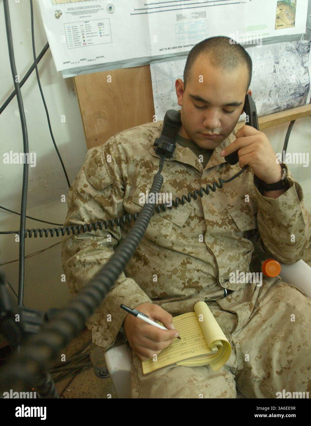 31 agosto 2004; Camp Mahmudiyah, Iraq; aggrovigliato nelle linee telefoniche è l'operatore radio Lance Cpl. MICHAEL A. MARTINEZ, che lavora nel 2nd Battalion, centro operativo del 2nd Marine Regiment. E' compito di Martinez trasmettere informazioni per tenere traccia delle loro unita' sul campo. Foto Stock