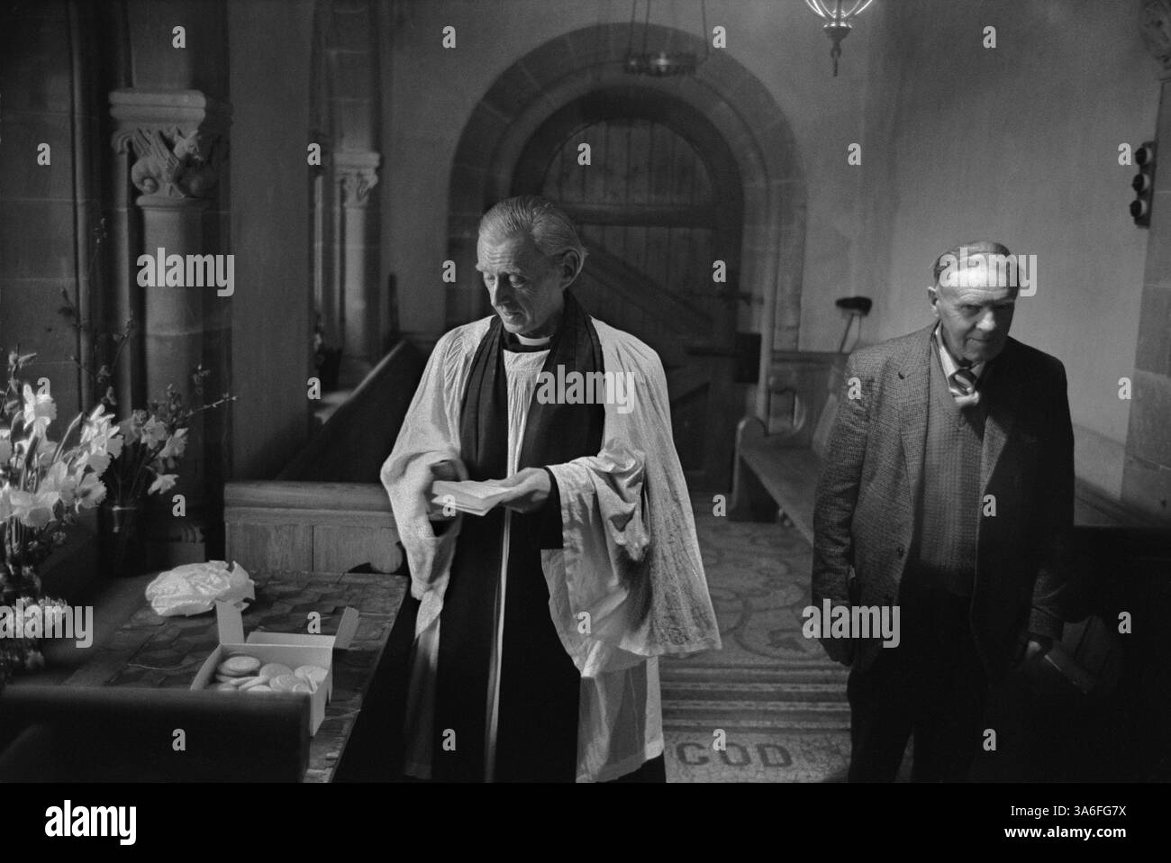 Palm Sunday Pax Cake distribuzione presso la chiesa di Santa Caterina, Hoarwithy, Herefordshire, Inghilterra 1974 UK 1970s. Il Revd. Idris Michael Evans, vicario dell'Hentland con Hoarwithy e il Sidesman Mr Stan Jones. Pax Cake (nella scatola di cartone a sinistra) è l'Agnus dei, l'Agnello di Dio. HOMER SYKES Foto Stock