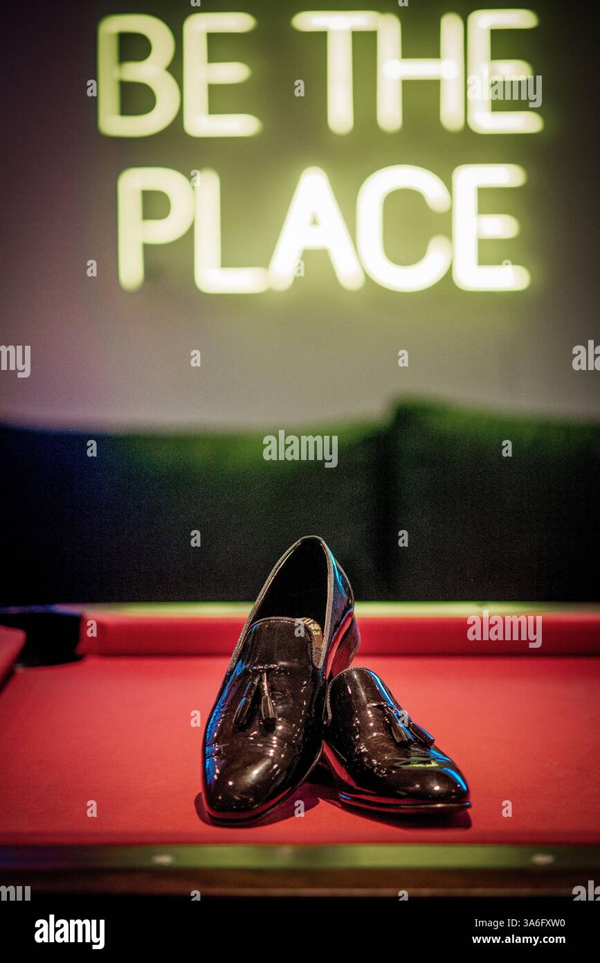 Scarpe da sposo lasciate su un tavolo da biliardo durante la preparazione dello sposo per il matrimonio Foto Stock