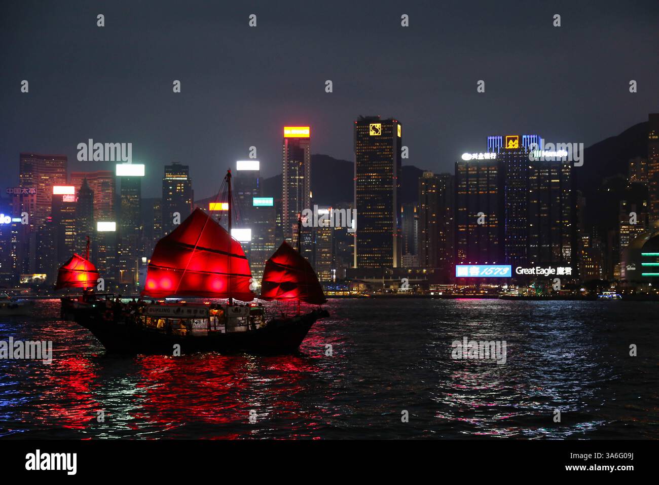 Barca a vela rossa illuminata e skyline della città di notte da Avenue of Stars, Hong Kong - 13 settembre 2024 Foto Stock