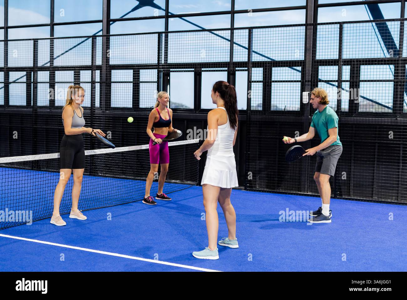 Gruppo di amici che giocano a tennis sul campo blu, godendo di uno stile di vita attivo Foto Stock