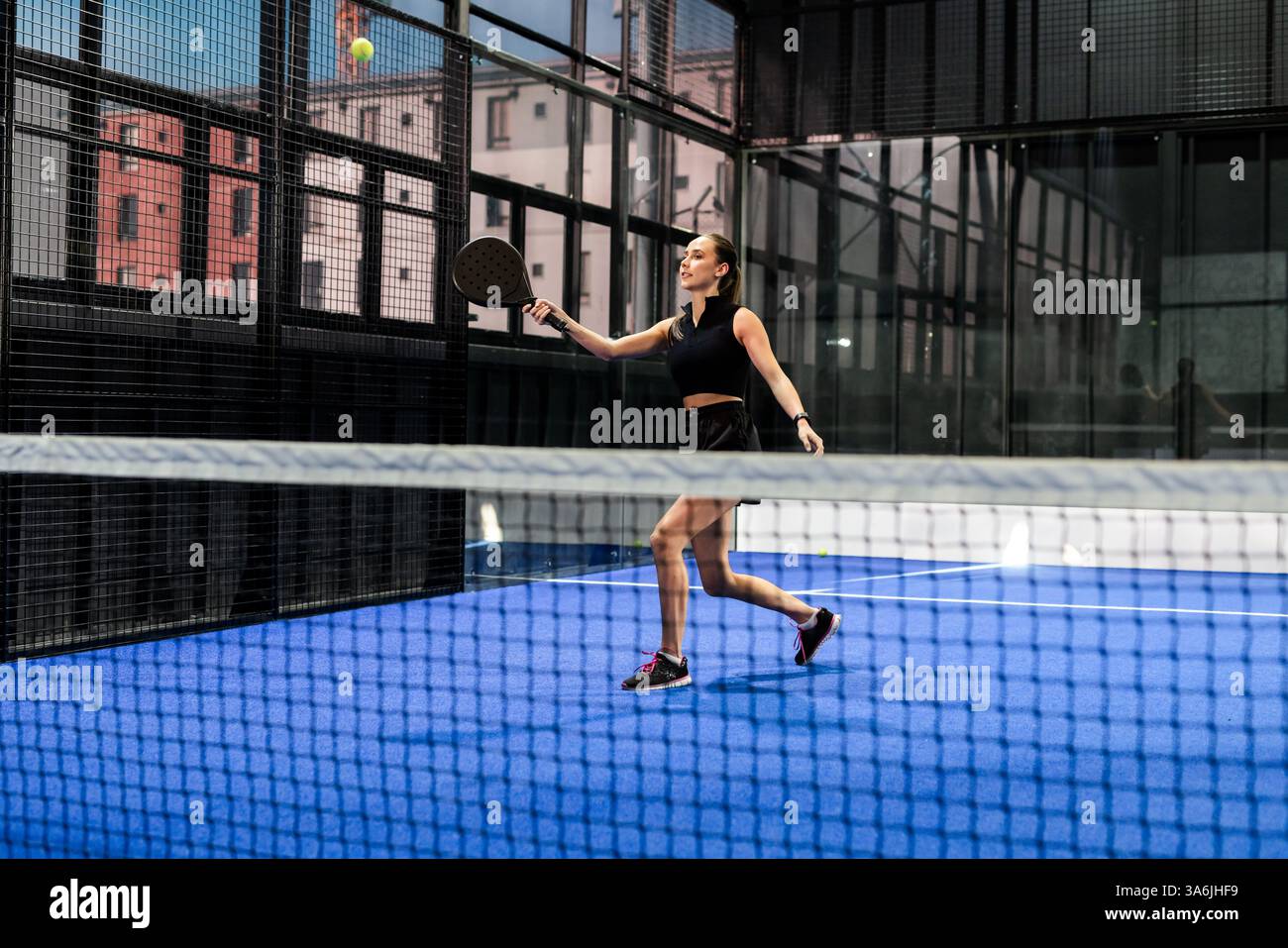 Donna che gioca a tennis in padel sul campo, concentrandosi sul colpire la palla con la racchetta Foto Stock