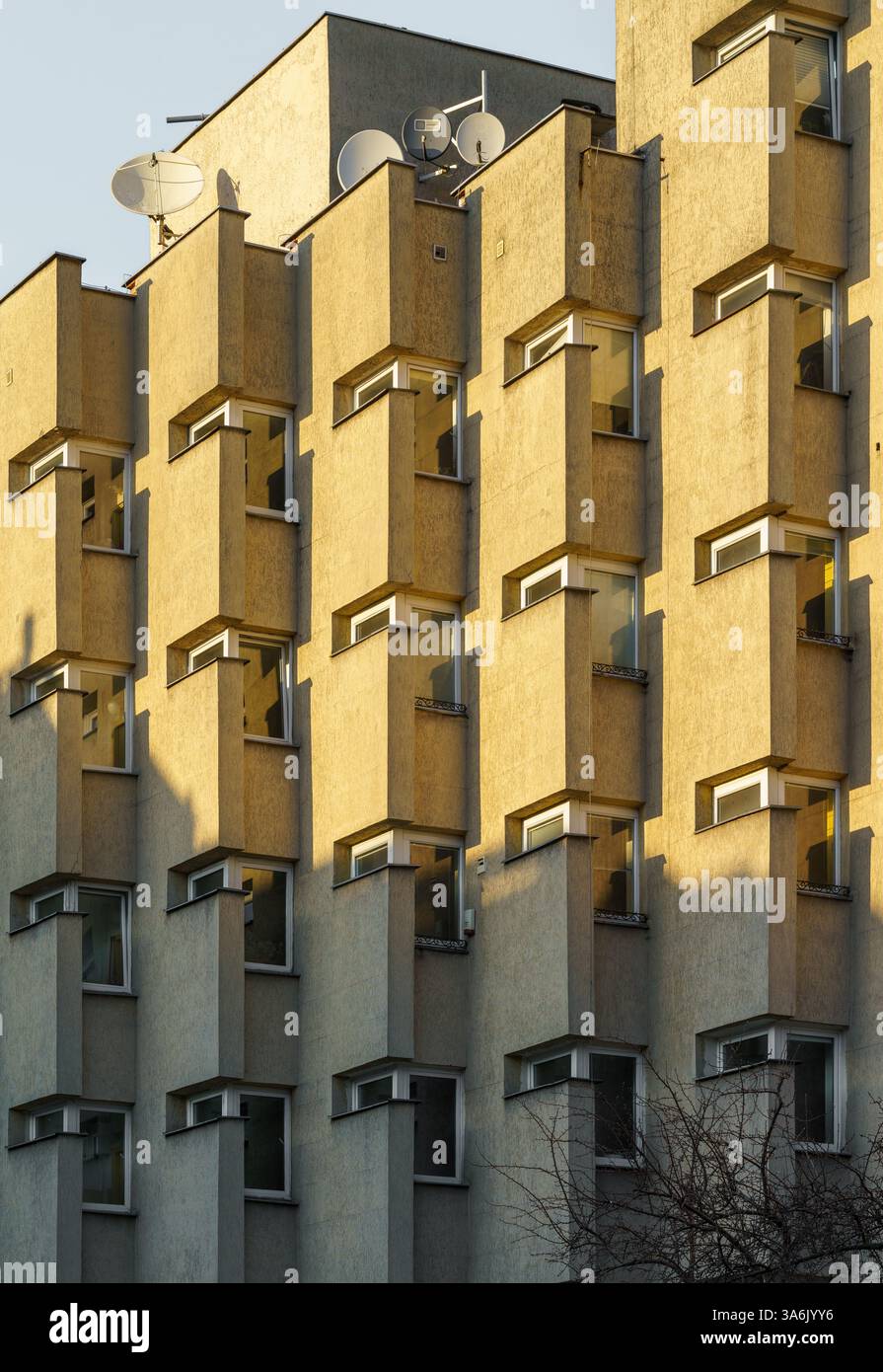 Facciata di un edificio insolito a Varsavia - esempio di moderna architettura socialista degli anni Settanta fotografata dalla calda luce del sole serale. Foto Stock