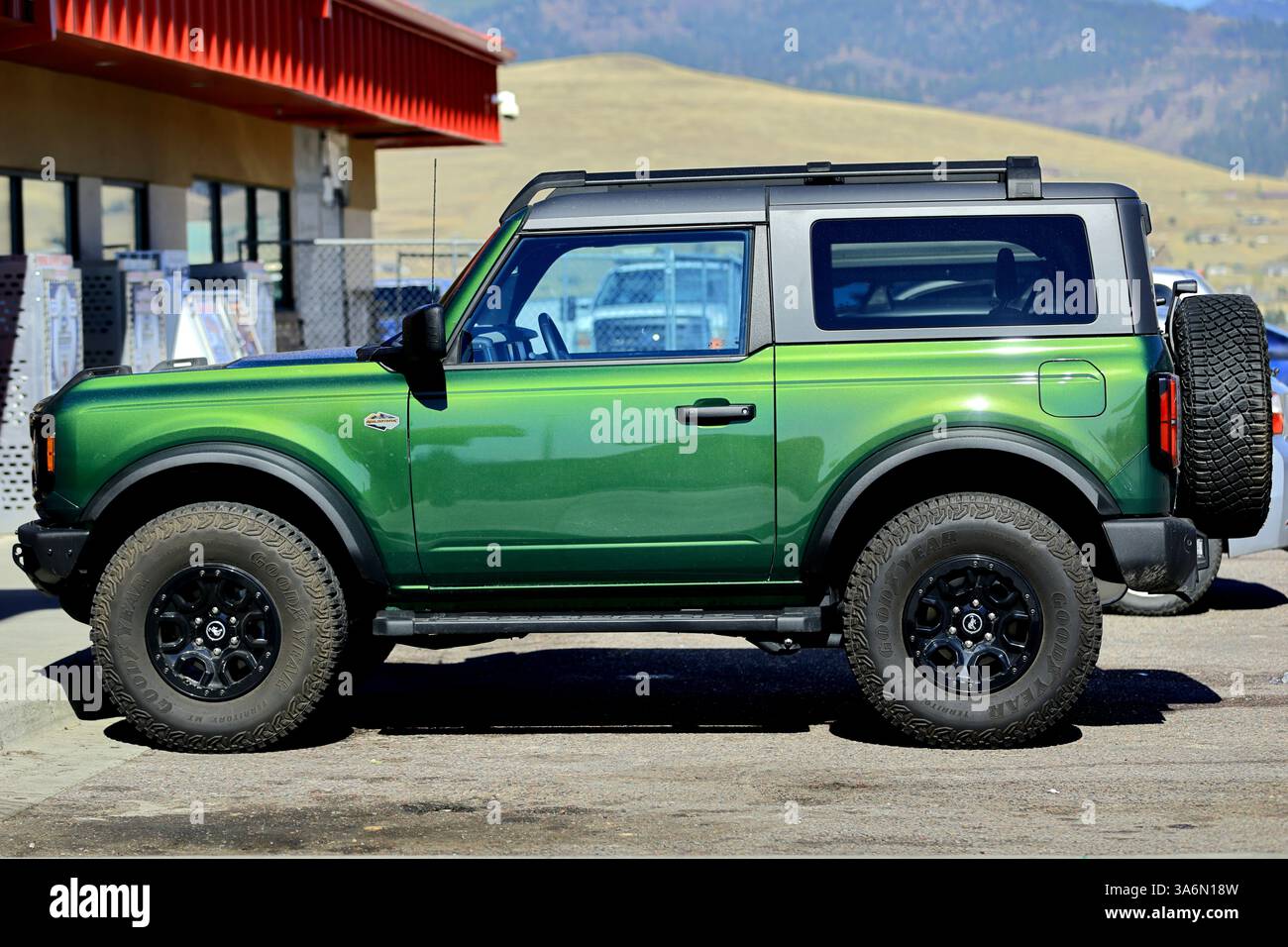 Una Ford Bronco verde vivace parcheggiata fuori da un negozio rurale, che mostra la sua struttura robusta, le capacità fuoristrada, il design pronto per l'avventura e lo stile audace. Foto Stock