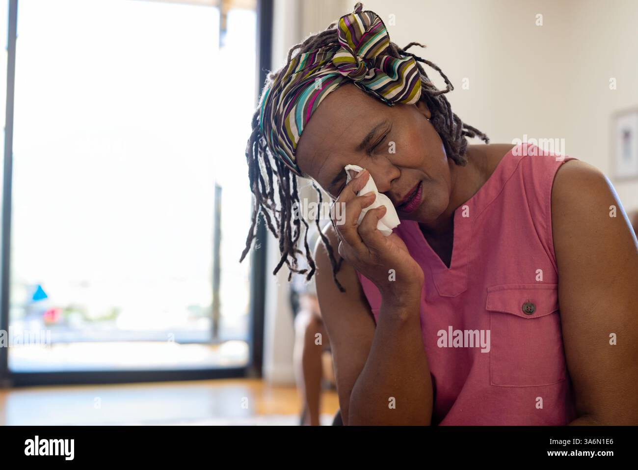 Donna anziana a casa che pulisce le lacrime con tessuto, sentendosi emotiva e riflessiva, copia spazio Foto Stock