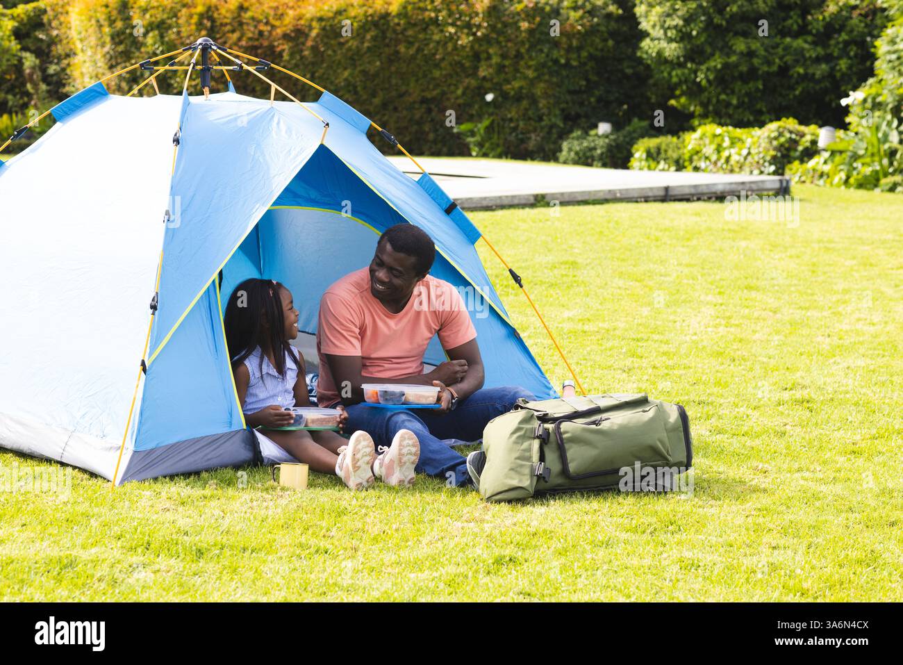 Padre e figlia si divertono in campeggio nel cortile, leggendo libri insieme Foto Stock