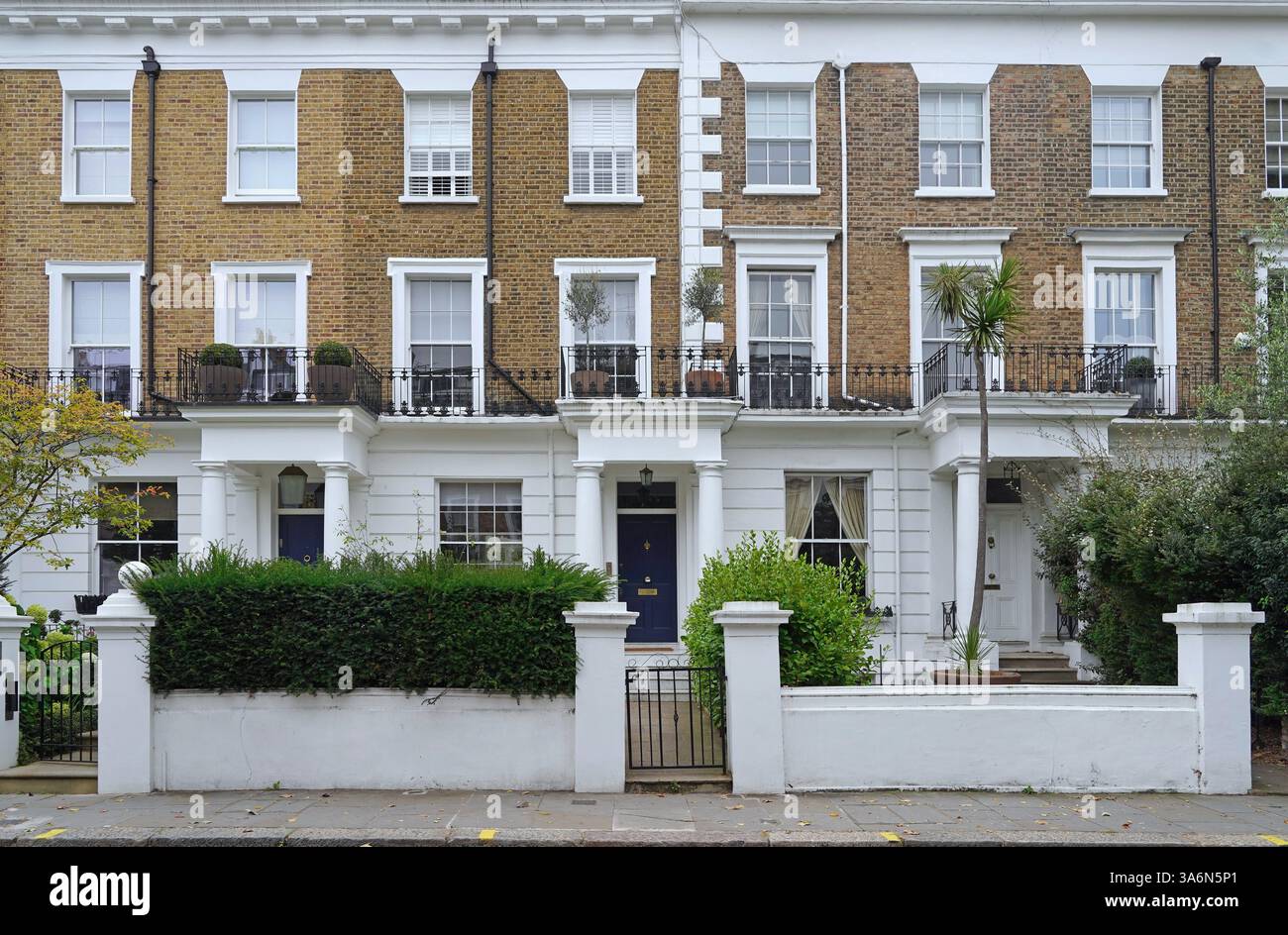 Una fila di case in mattoni e stucco nel centro di Londra con giardini frontali murati Foto Stock