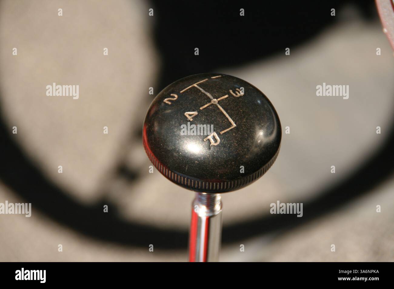 Un pomello del cambio a quattro velocità e l'ombra di un volante su una jeep vintage. Foto Stock