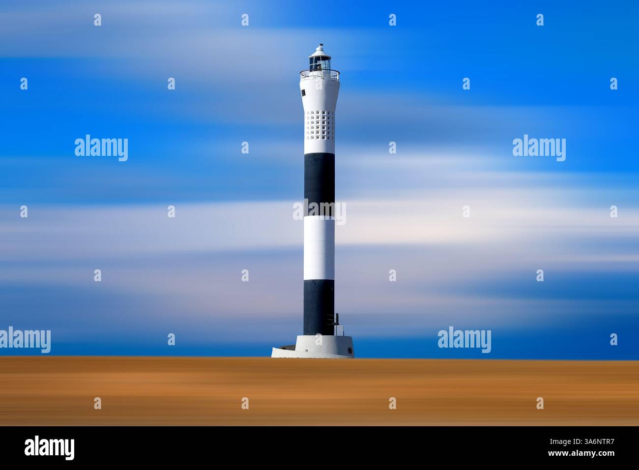 Alto faro bianco e nero sulla spiaggia astratta con un cielo blu e bianco luminoso, la spiaggia e il cielo hanno movimento in loro mentre la casa di luce è dentro Foto Stock
