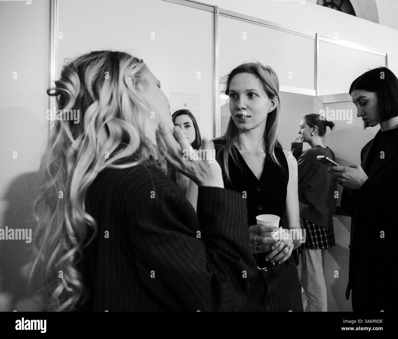 Kiev, Ucraina - 14 febbraio 2025: Backstage alla settimana della moda Ucraina, le modelle chiacchierano mentre gli stilisti aggiungono tocchi finali, creando un'atmosfera di creatività ed eccitazione alla moda. Foto Stock