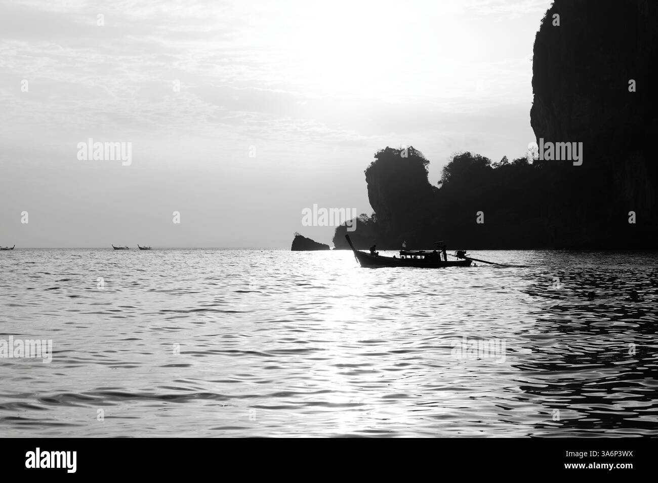 La barca a coda lunga attraversa acque scintillanti incorniciate da torreggianti scogliere e da un cielo lunare a Tonsai Foto Stock