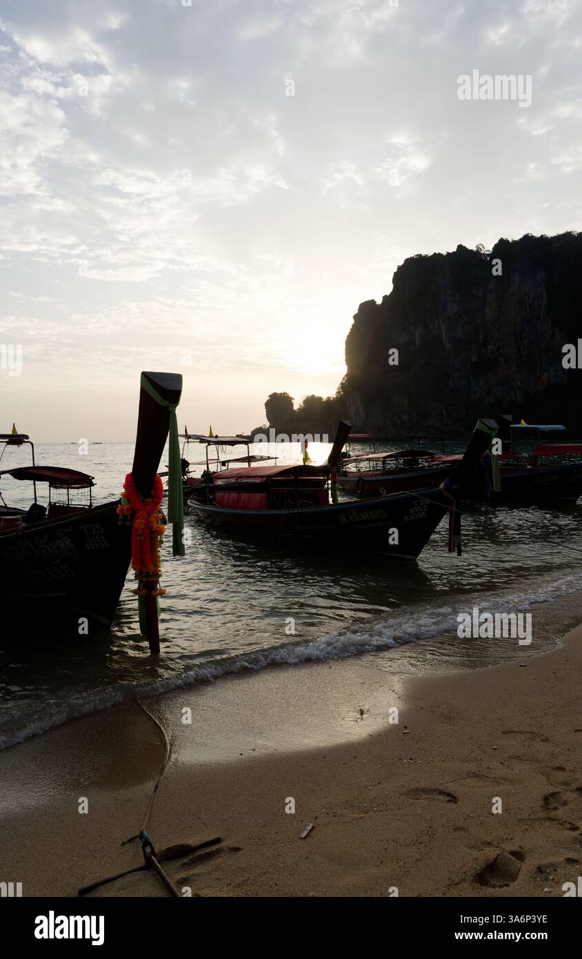 Le barche a coda lunga riposano sulla riva al tramonto a Tonsai, i loro archi adornati di ghirlande Foto Stock