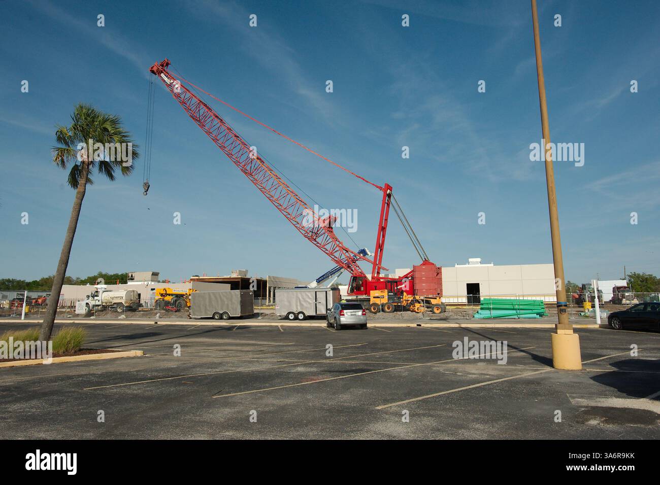 Vista della gru a traliccio rossa dal parcheggio con una palma a sinistra e diversi edifici sullo sfondo. Solo per uso editoriale, 22 marzo 2025 S. Foto Stock