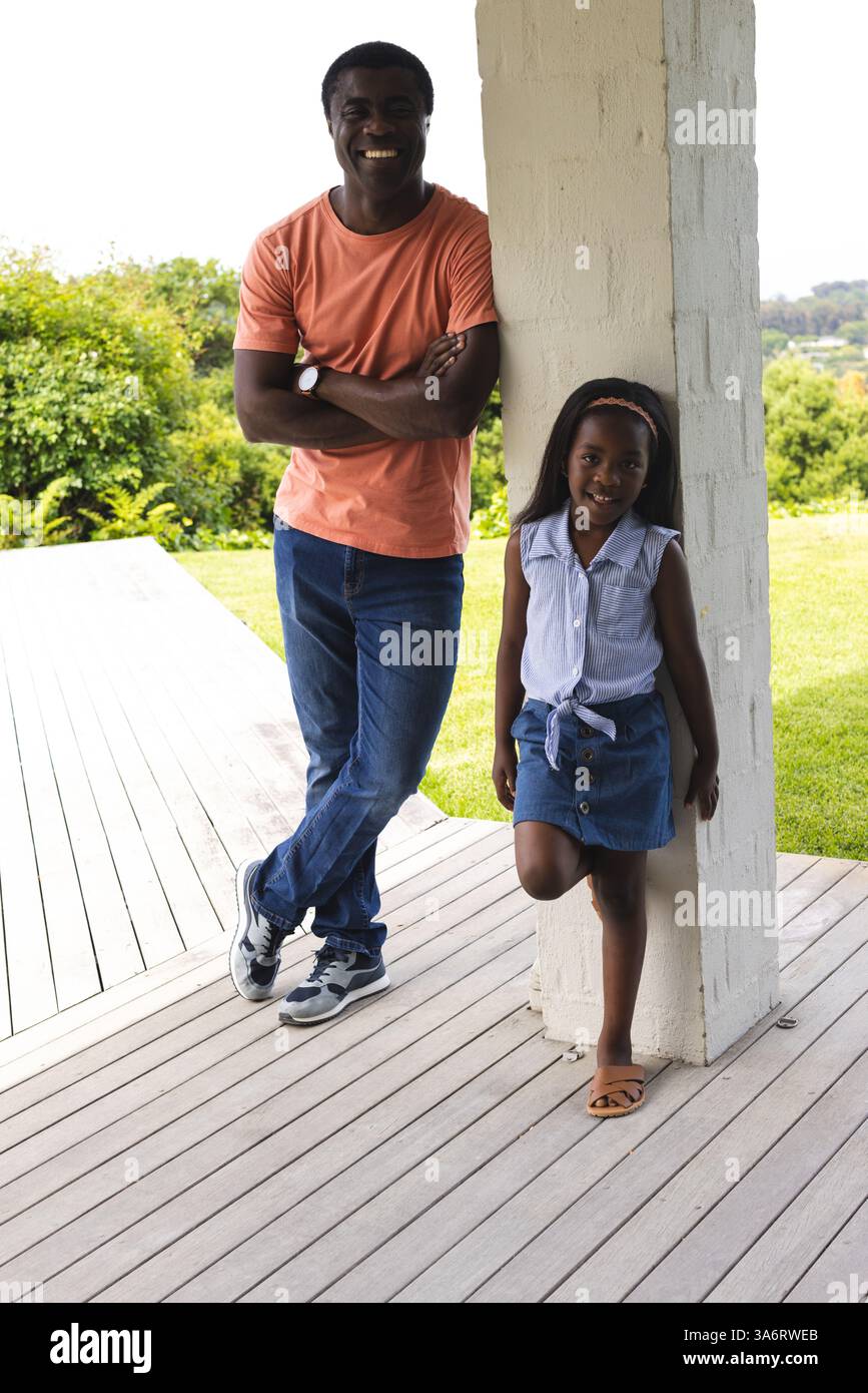 Padre e figlia si divertono all'aria aperta insieme, sorridono e si rilassano sul portico Foto Stock