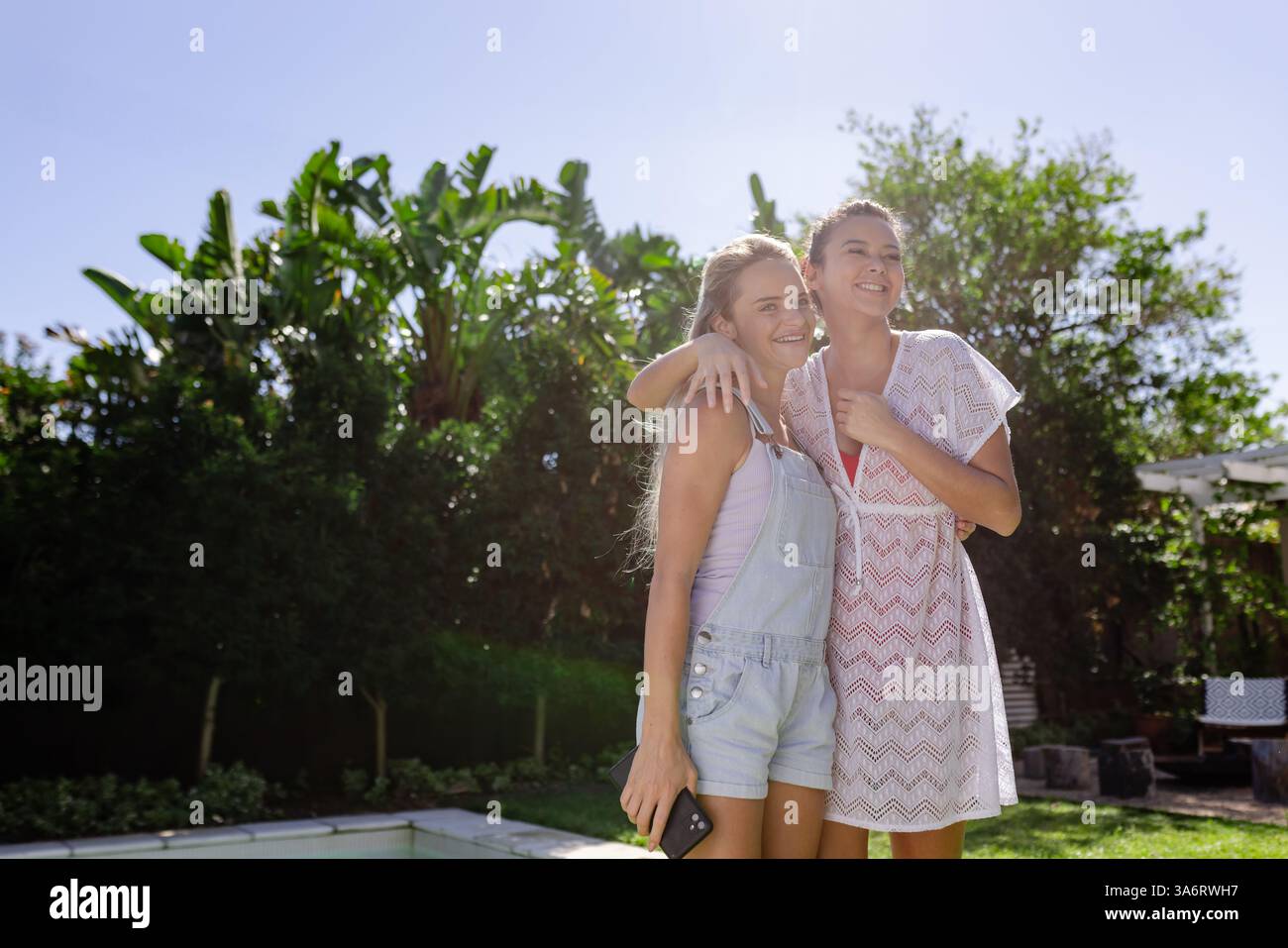 Due amiche che ridono e si godono una giornata di sole a bordo piscina, spazio fotocopie Foto Stock