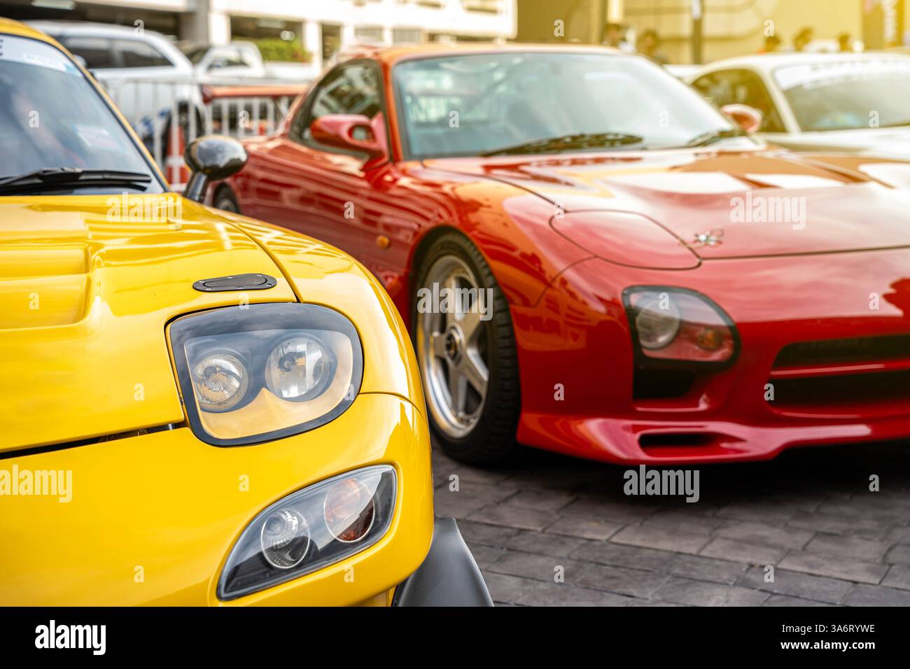 Auto moderne gialle e rosse Vista ravvicinata dei fari e dei raggi solari parcheggiati all'aperto, auto nuove di zecca in vendita. Foto Stock