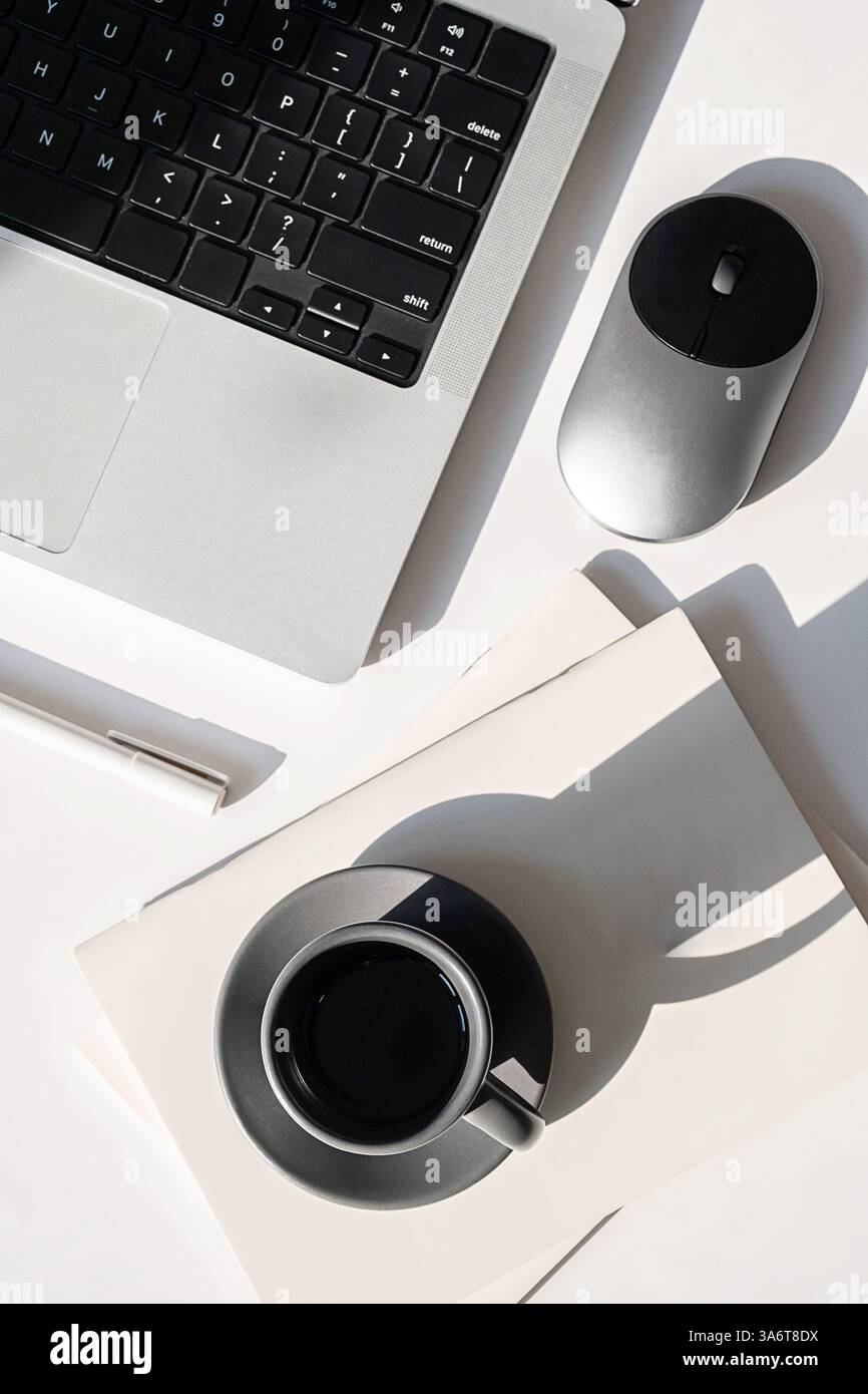 Costo aggiuntivo della scrivania minimalista. Laptop, Planner, tazza da caffè e mouse su una moderna scrivania bianca. Foto Stock