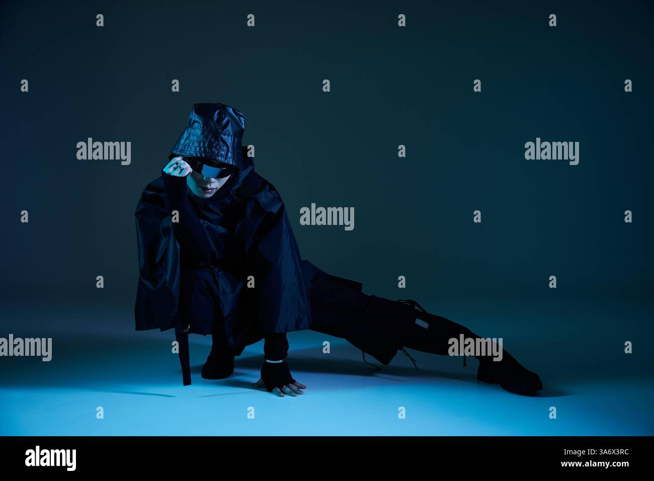 L'uomo elegante, vestito con un elegante abito nero, è in posa artistica con un'espressione sicura. Foto Stock