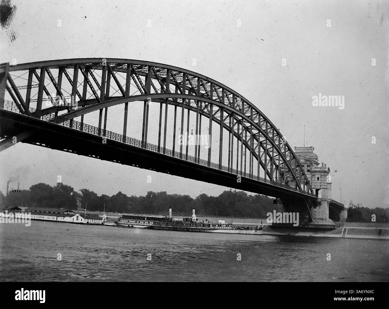 Una delle tre campate di un ponte sul Reno a Dusseldorf, in Germania. In procinto di passare sotto c'è un piroscafo a pale. L'Oberkasseler Brücke, era una struttura notevole che collegava la città al distretto di Oberkassel. Era un ponte sospeso con tre campate, progettato per ospitare sia il traffico pedonale che quello veicolare. Questo ponte giocò un ruolo significativo nelle infrastrutture della città fino a quando fu distrutto durante la seconda guerra mondiale e successivamente sostituito da un moderno ponte strallato. Da una raccolta di fotografie tratte da un tour europeo di famiglia che si è svolto nel 1899. Foto Stock