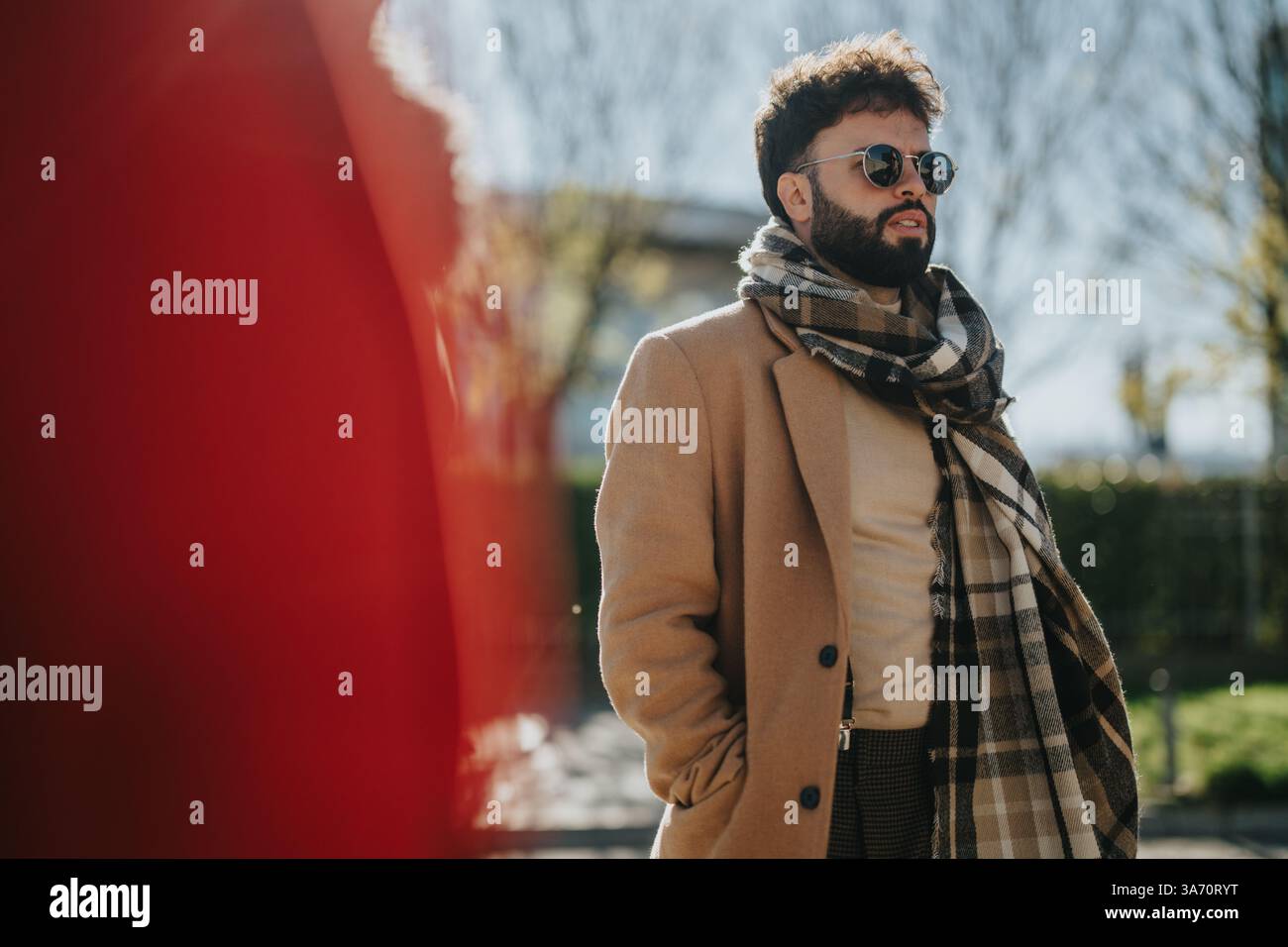 Uomo elegante con sciarpa a scacchi e occhiali da sole in piedi con sicurezza all'aperto Foto Stock